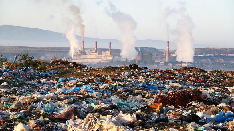 Discarica a cielo aperto con fabbriche sullo sfondo